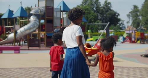 Woman walking outside with two children